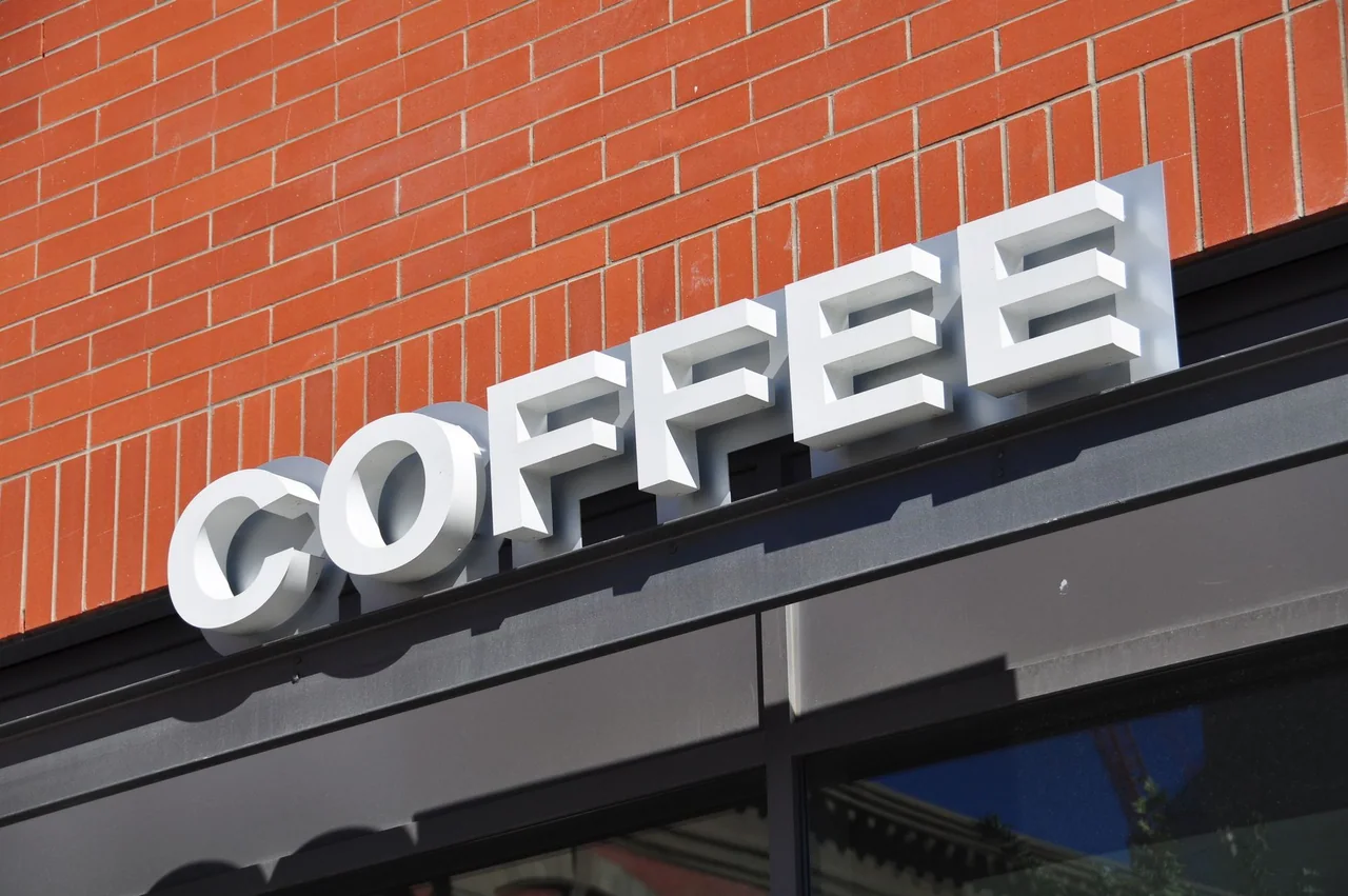 White raised COFFEE lettering above a storefront on a brick facade